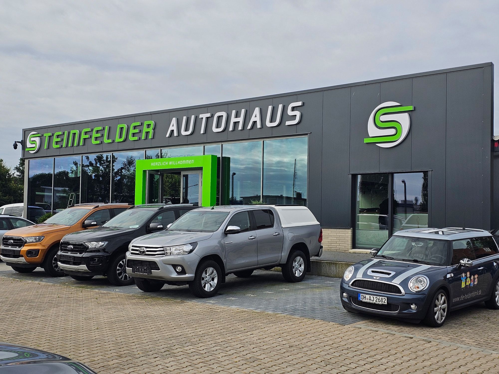 Das Steinfelder Autohaus von vorne mit ein paar Gebrauchtwagen im Vordergrund